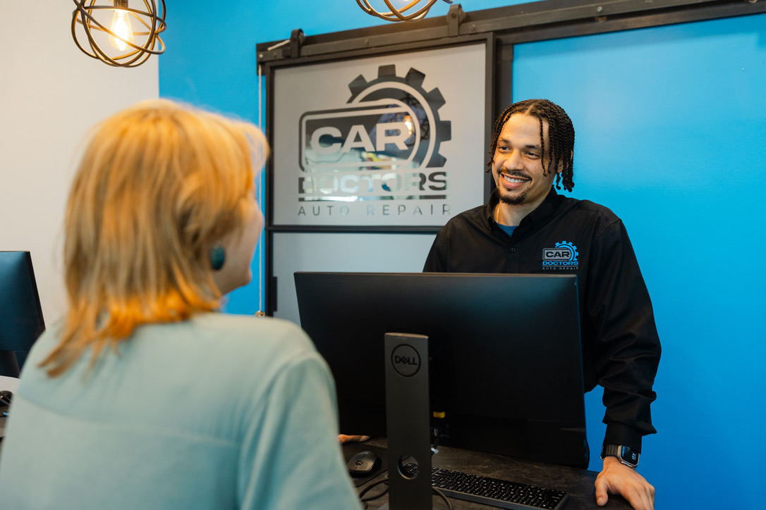 A Car Doctors Advisor helps a customer in need of car maintenance at the front desk.